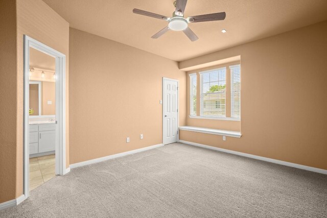 unfurnished bedroom with ceiling fan, light carpet, and connected bathroom