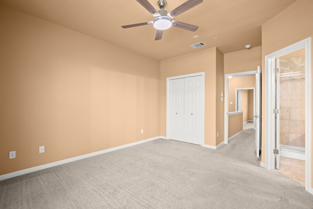 unfurnished bedroom featuring connected bathroom, light colored carpet, a closet, and ceiling fan