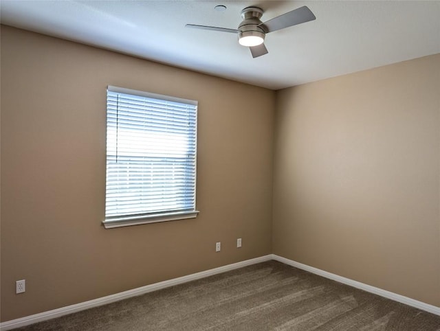 carpeted spare room featuring ceiling fan and baseboards