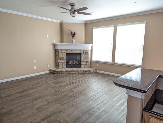 unfurnished living room featuring baseboards, a stone fireplace, wood finished floors, and crown molding