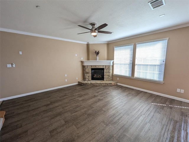 unfurnished living room featuring visible vents, dark wood finished floors, crown molding, and a stone fireplace