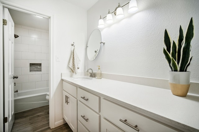 full bathroom with tiled shower / bath, hardwood / wood-style flooring, vanity, and toilet