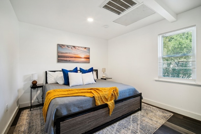 bedroom with beamed ceiling and dark wood-type flooring