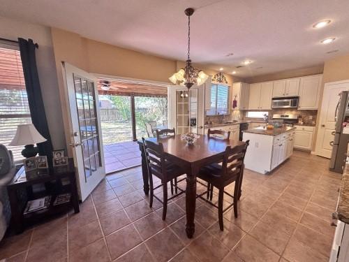 tiled dining space with french doors and a notable chandelier