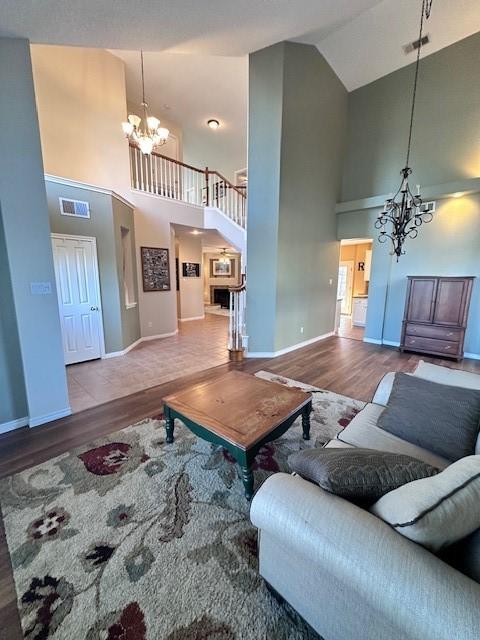 living room featuring high vaulted ceiling, a notable chandelier, and wood-type flooring