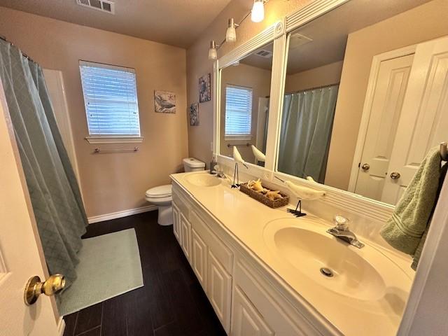 bathroom featuring wood-type flooring, plenty of natural light, vanity, and toilet