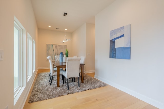 dining space featuring a healthy amount of sunlight, wood-type flooring, and a chandelier