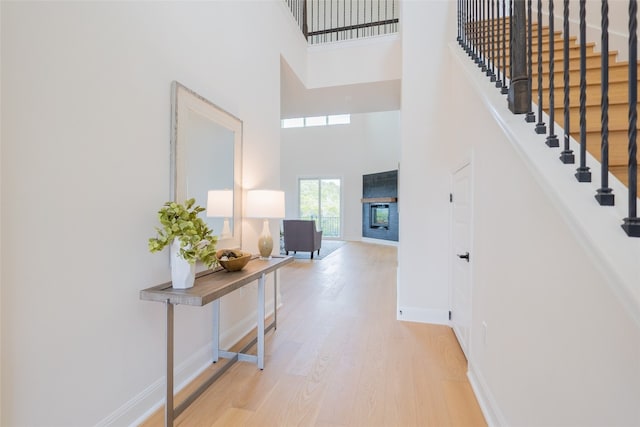 foyer entrance featuring hardwood / wood-style flooring, a towering ceiling, and a tiled fireplace