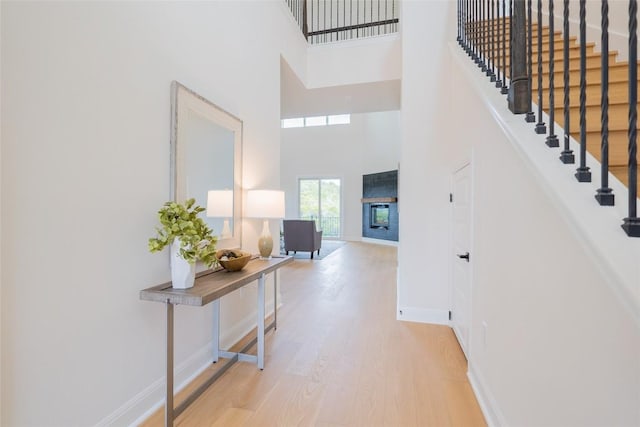 entryway with stairs, a high ceiling, baseboards, and wood finished floors