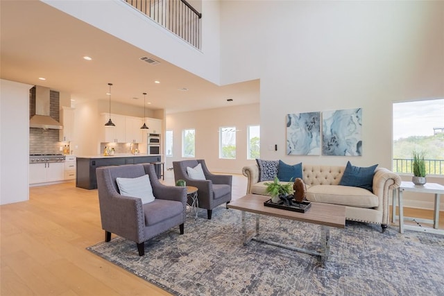 living room featuring a high ceiling and light wood-type flooring