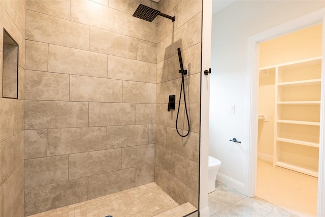 bathroom featuring tile patterned flooring, toilet, and a tile shower