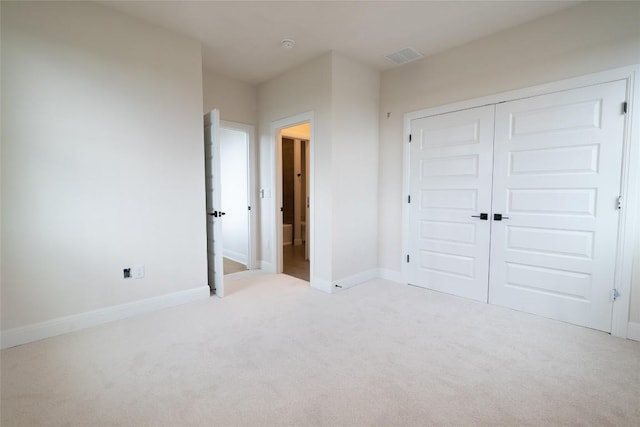 unfurnished bedroom with light carpet and a closet