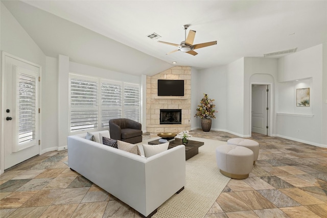 living room with ceiling fan, a stone fireplace, lofted ceiling, and a wealth of natural light