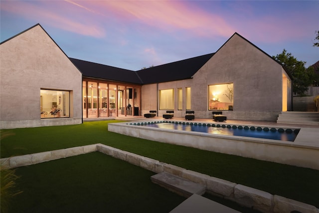 pool at dusk featuring a yard and a patio area