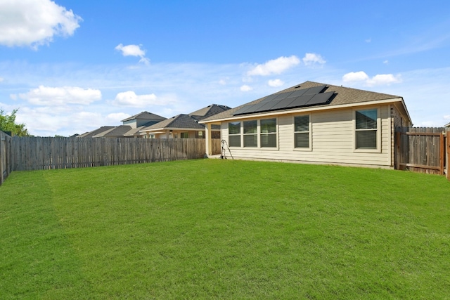 back of house with a lawn and solar panels