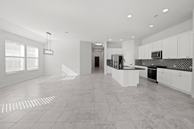 kitchen with white cabinets, appliances with stainless steel finishes, a center island with sink, and hanging light fixtures