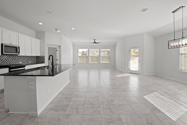 kitchen featuring white cabinets, pendant lighting, sink, and an island with sink