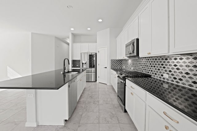 kitchen featuring sink, stainless steel appliances, tasteful backsplash, an island with sink, and white cabinets