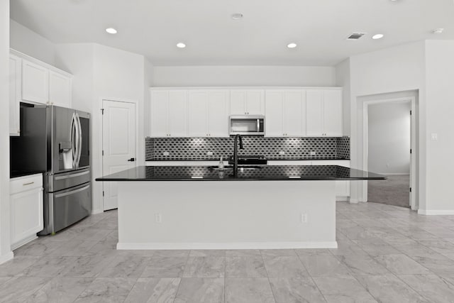 kitchen featuring white cabinetry, decorative backsplash, a kitchen island with sink, and appliances with stainless steel finishes