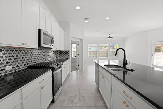 kitchen featuring white cabinets, appliances with stainless steel finishes, dark stone countertops, and sink