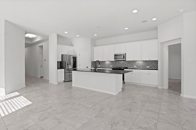 kitchen with white cabinetry, sink, a kitchen island with sink, decorative backsplash, and appliances with stainless steel finishes