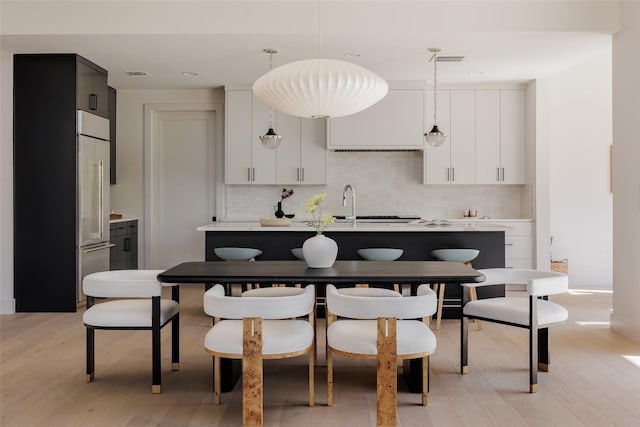 kitchen featuring white cabinets, light hardwood / wood-style flooring, pendant lighting, and tasteful backsplash