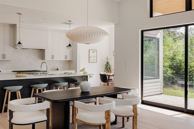 kitchen featuring decorative light fixtures, light hardwood / wood-style floors, white cabinetry, and tasteful backsplash