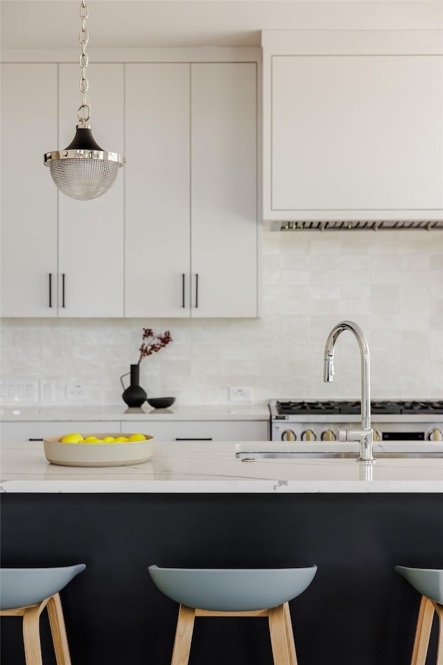 kitchen featuring hanging light fixtures, white cabinets, a breakfast bar area, and tasteful backsplash