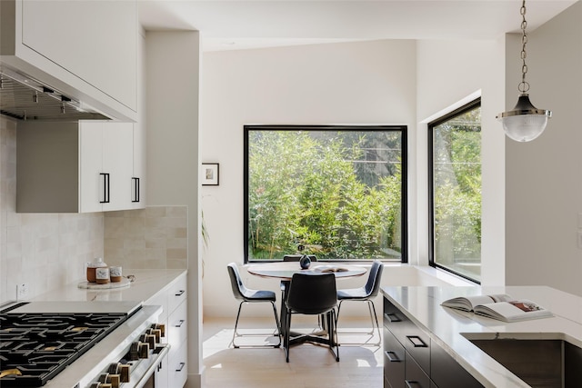 kitchen featuring decorative light fixtures, white cabinetry, high end range, and decorative backsplash