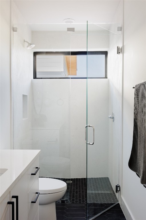 bathroom featuring a shower with shower door, tile patterned floors, toilet, and vanity