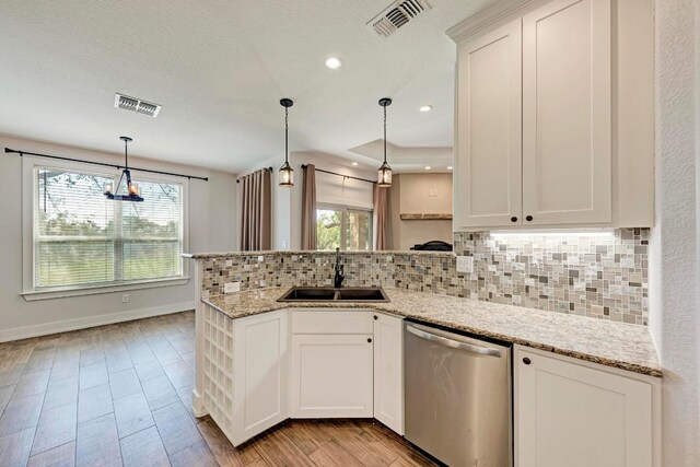 kitchen featuring stainless steel dishwasher, white cabinetry, sink, and pendant lighting