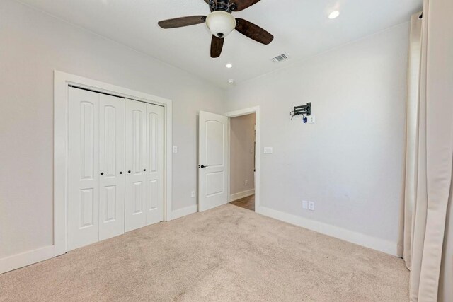 unfurnished bedroom featuring a closet, ceiling fan, and light colored carpet