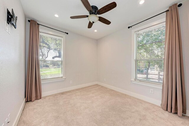 carpeted spare room featuring ceiling fan and a wealth of natural light