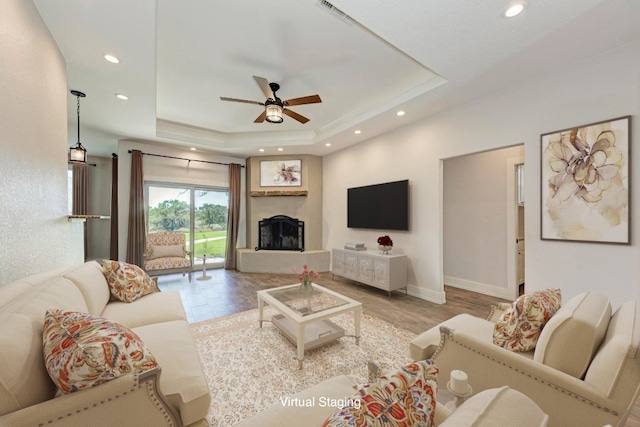 living room featuring light hardwood / wood-style floors, a tray ceiling, and ceiling fan