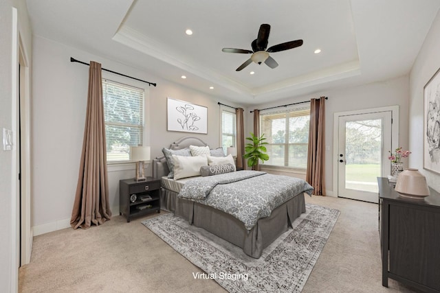 bedroom with multiple windows, a tray ceiling, ceiling fan, and access to exterior