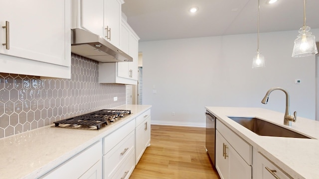 kitchen with sink, hanging light fixtures, light hardwood / wood-style flooring, appliances with stainless steel finishes, and white cabinetry