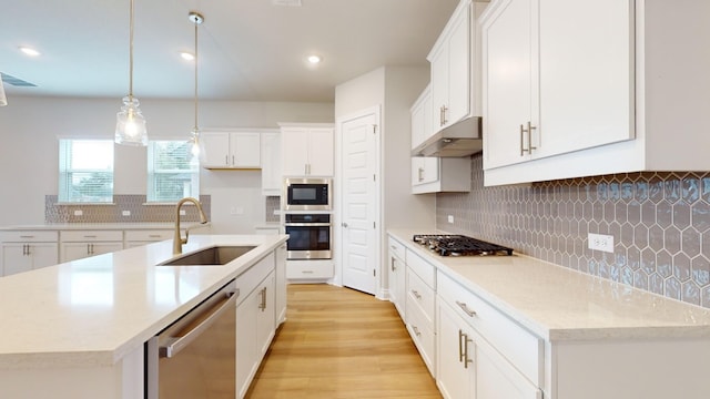 kitchen featuring white cabinetry, sink, stainless steel appliances, an island with sink, and light hardwood / wood-style floors