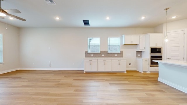 kitchen with light wood-type flooring, built in microwave, pendant lighting, white cabinets, and oven