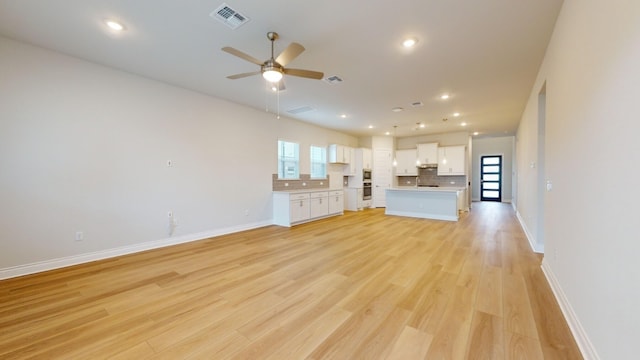 unfurnished living room featuring light wood-type flooring, a wealth of natural light, and ceiling fan