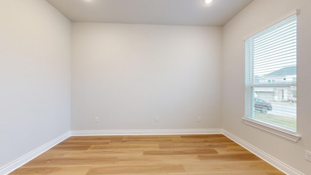 empty room with a wealth of natural light and light hardwood / wood-style floors