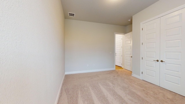 unfurnished bedroom featuring a closet and light colored carpet