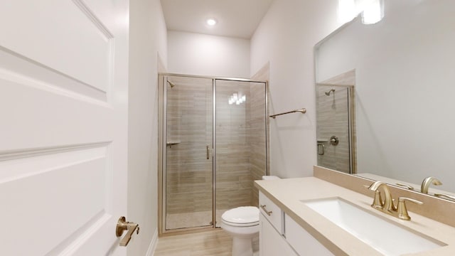 bathroom featuring hardwood / wood-style flooring, vanity, a shower with shower door, and toilet