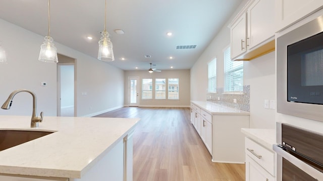 kitchen featuring tasteful backsplash, stainless steel appliances, ceiling fan, decorative light fixtures, and white cabinets