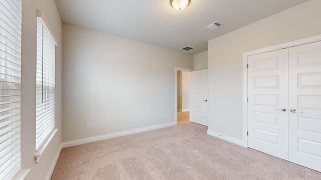 unfurnished bedroom with light carpet and a closet