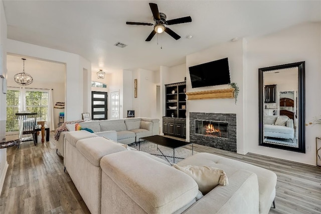 3110 Point Cv, Lago Vista, TX 78645 - living room featuring wood finished floors, ceiling fan, a stone fireplace, and a chandelier