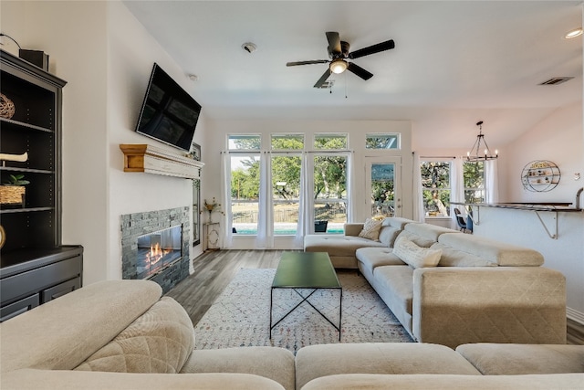 living room with ceiling fan with notable chandelier, a wealth of natural light, and hardwood / wood-style flooring