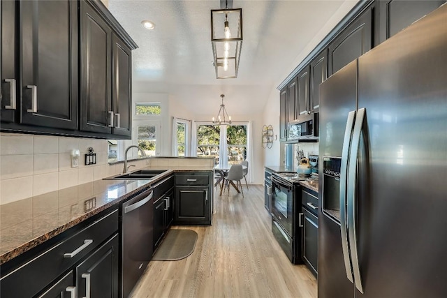 3110 Point Cv, Lago Vista, TX 78645 - kitchen featuring appliances with stainless steel finishes, a chandelier, light wood-style floors, backsplash, and dark stone countertops