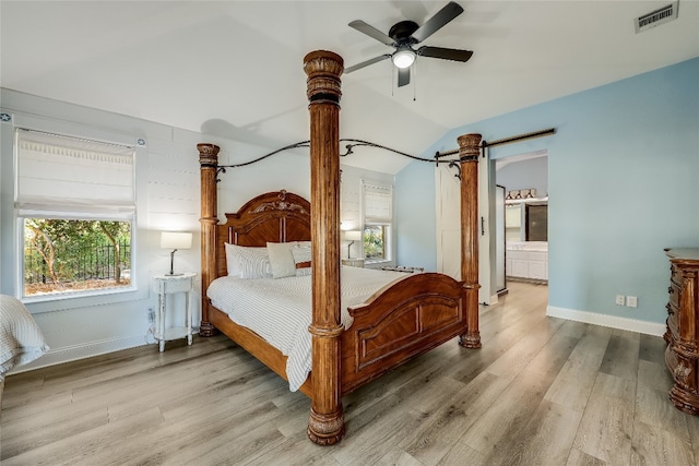 bedroom featuring light wood-type flooring, lofted ceiling, ceiling fan, and ensuite bathroom