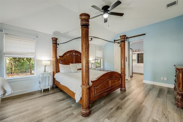 3110 Point Cv, Lago Vista, TX 78645 - bedroom featuring wood finished floors, vaulted ceiling, a ceiling fan, connected bathroom, and a barn door