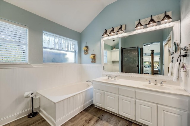 3110 Point Cv, Lago Vista, TX 78645 - bathroom with wainscoting, wood finished floors, a bath, double vanity, and lofted ceiling